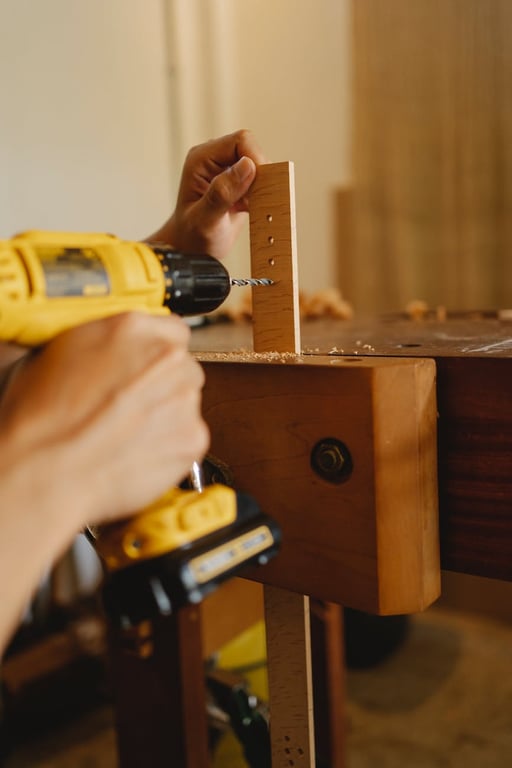 Homme anonyme et habile utilisant un tournevis tout en perçant des trous dans une pièce de bois dans un atelier.